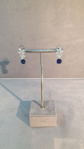 Jewelry set with floral earrings and a brooch on a textured beige background