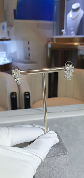 Decorative metal stand with floral designs held by a gloved hand against a blurred indoor background.