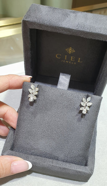 Gray jewelry box with a floral earring inside, held by a hand.