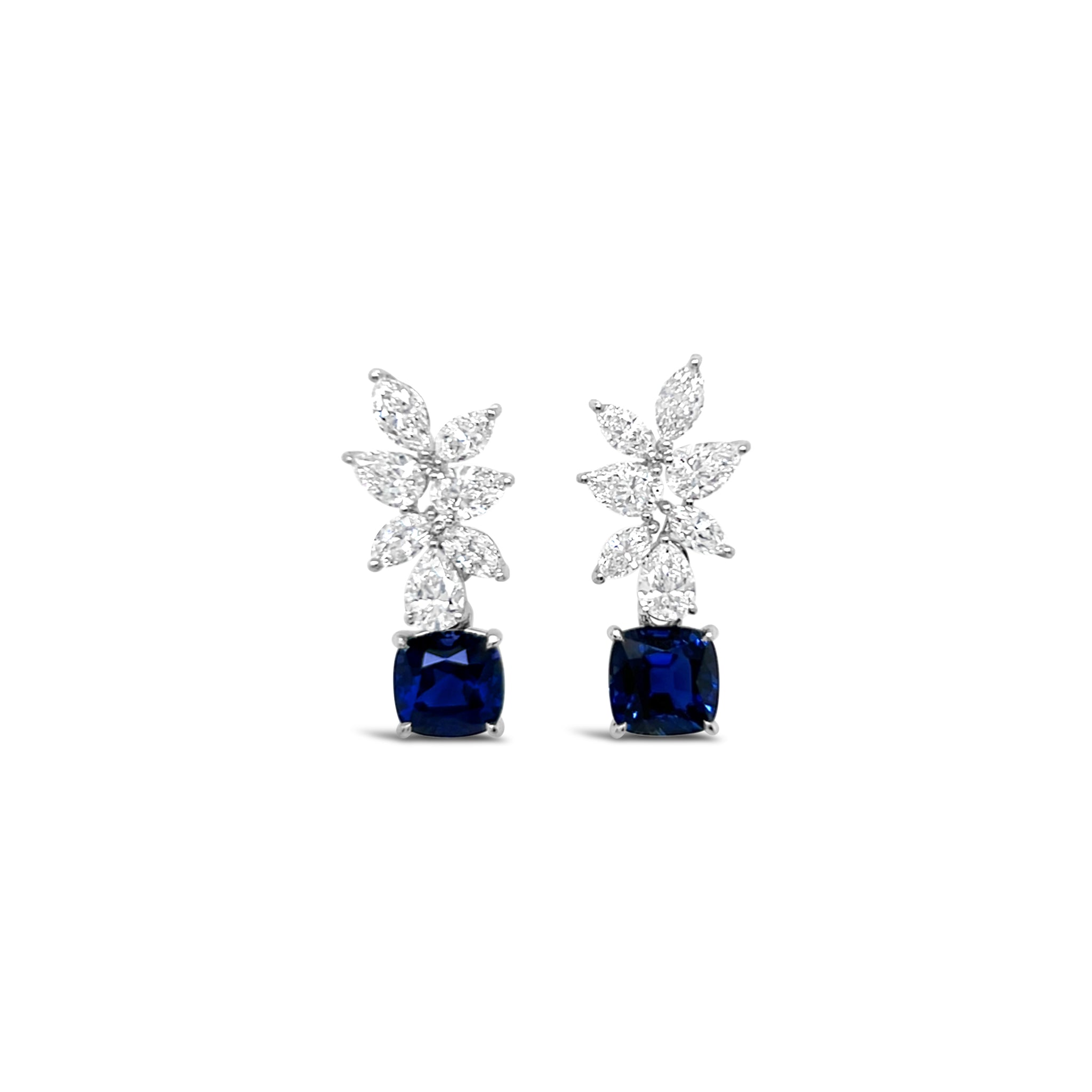 Pair of earrings with blue gemstones and diamond-like elements on a white background